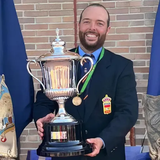 Campeón de tiro deportivo mostrando trofeo en competición oficial. Formación basada en excelencia, disciplina y resultados en el deporte de precisión