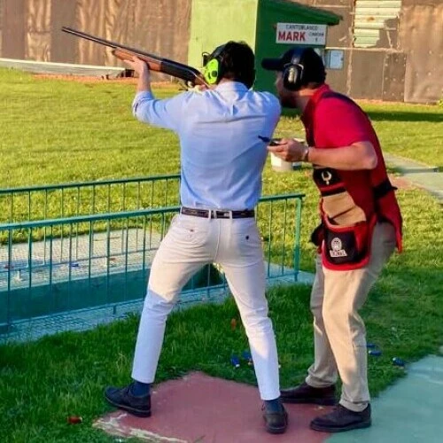 Clase de iniciación al tiro al plato en Madrid, con instructor profesional guiando al alumno en campo oficial bajo normas de seguridad